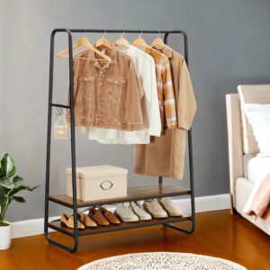 Black metal clothing rack with beige and brown outfits on hangers, a storage box on the middle shelf and shoes on the bottom shelf.